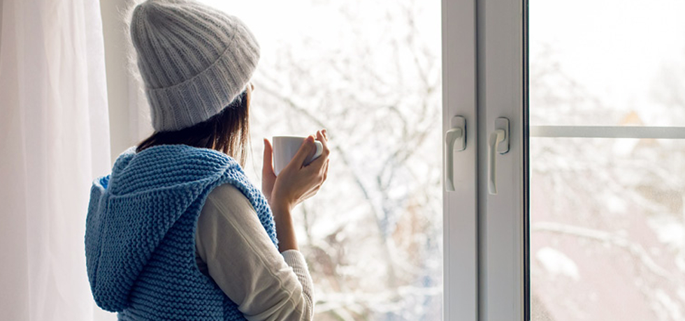 A woman looking out of a window during winter.