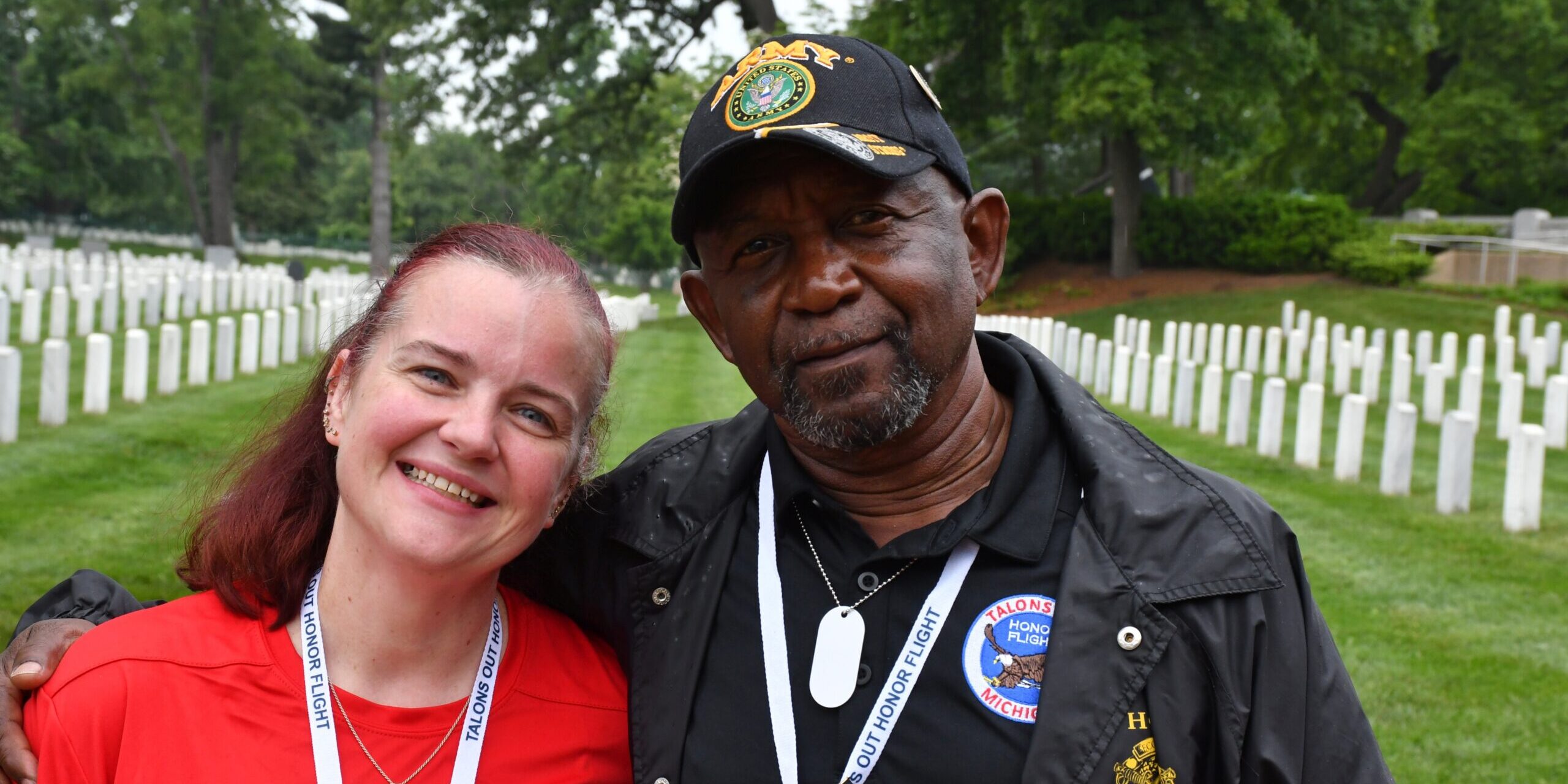 A woman in a red shirt smiles for a photo with a U.S. Army veteran.