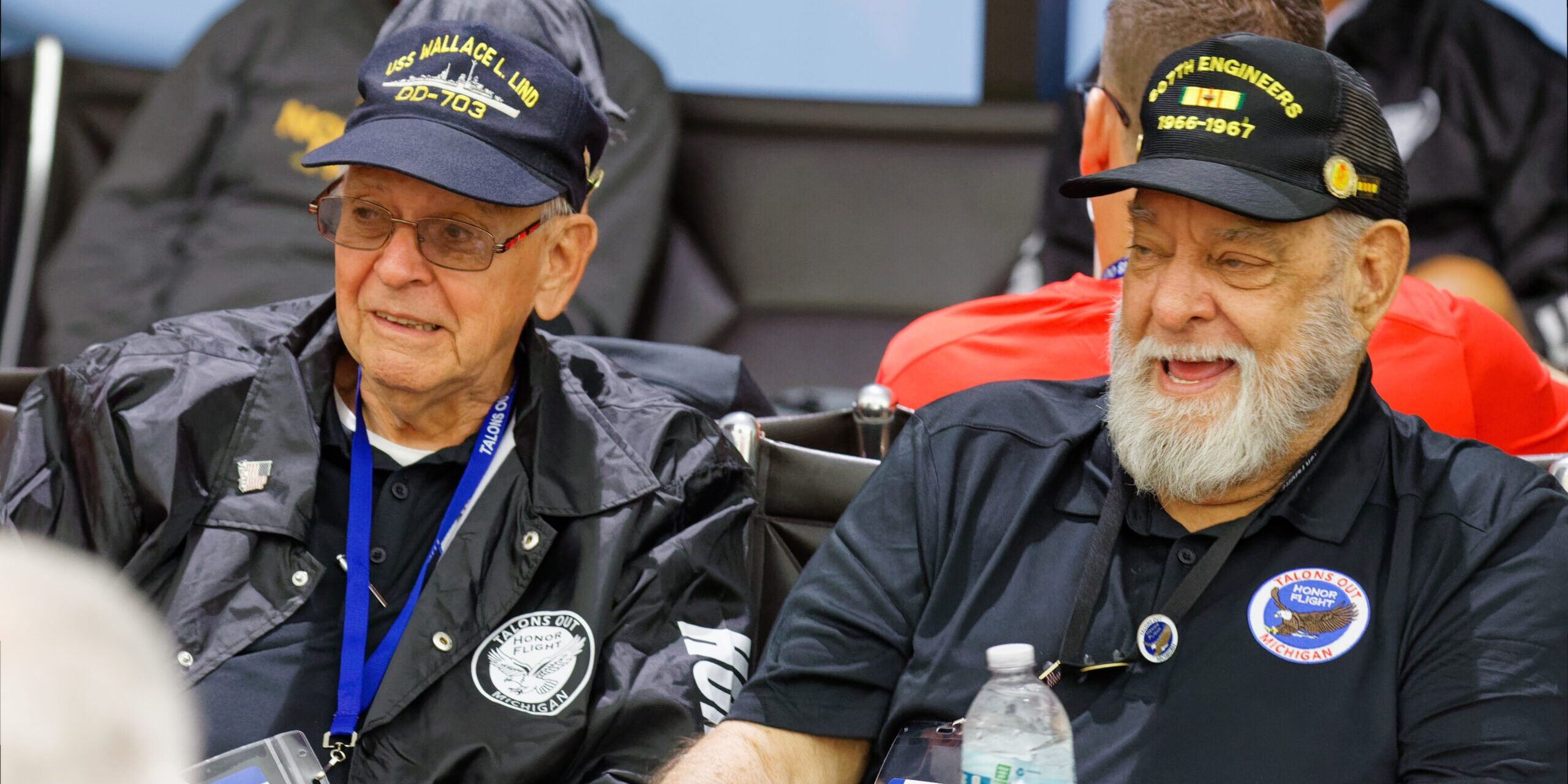 Two military veterans sit next to each other in an airport.