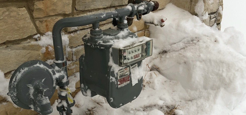 A natural gas meter with snow cleared away from around it.