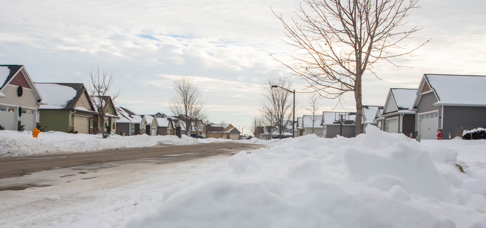 A photo of a snowy neighborhood on a partly cloudy day.
