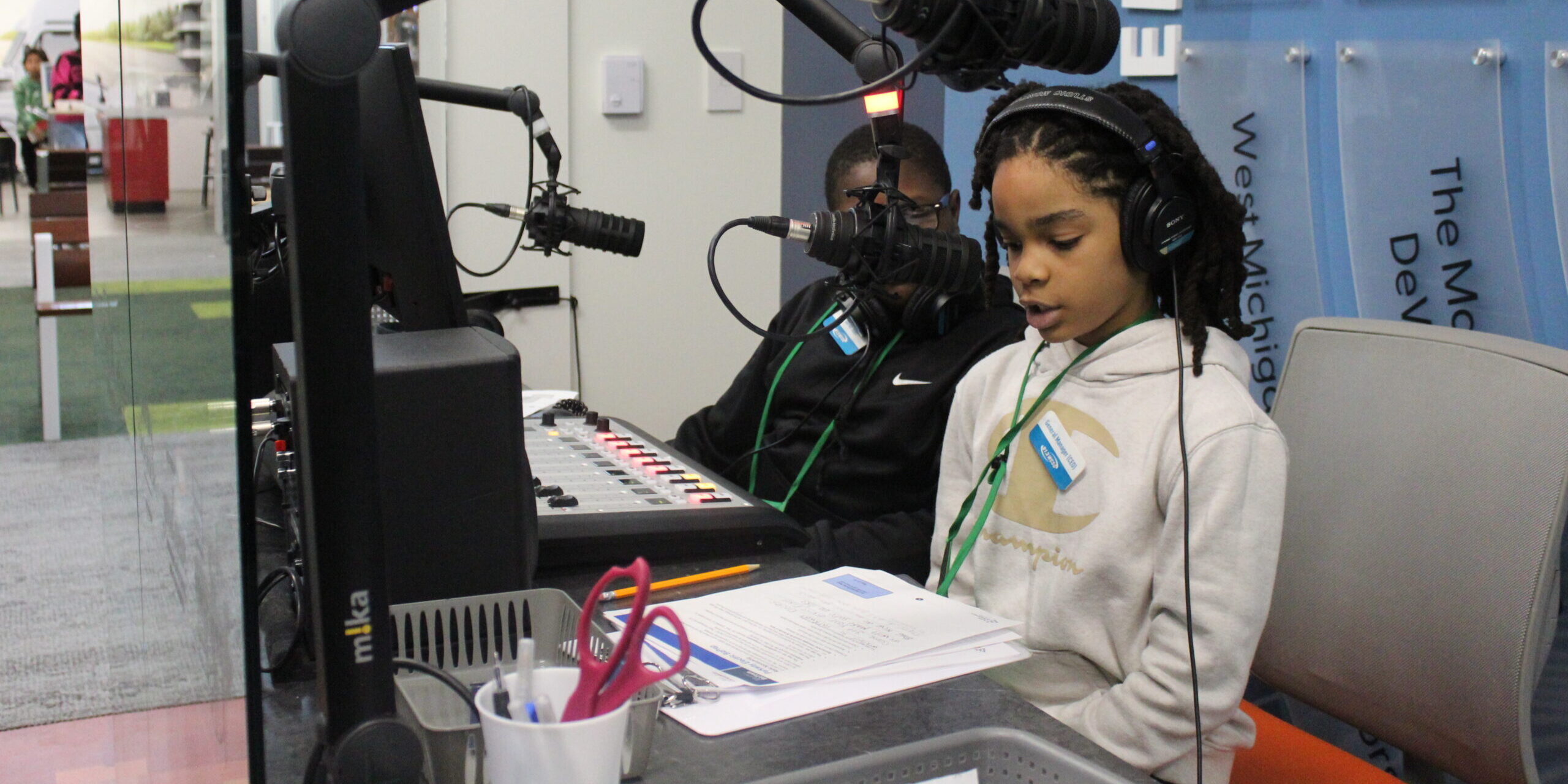 A child reads a paragraph into a radio microphone at a Junior Achievement learning center.